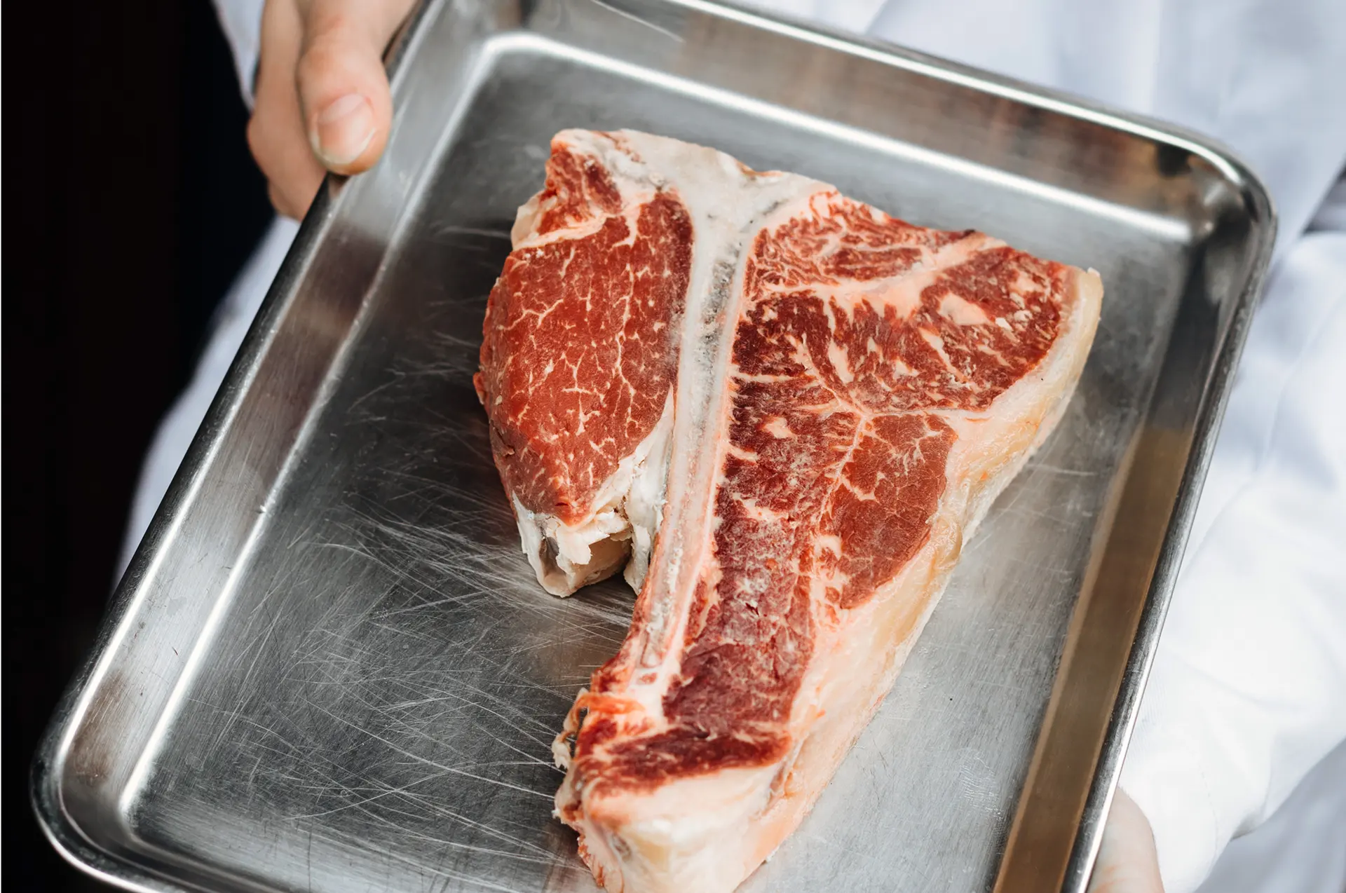 Syrový T-bone steak na kovovém tácku.